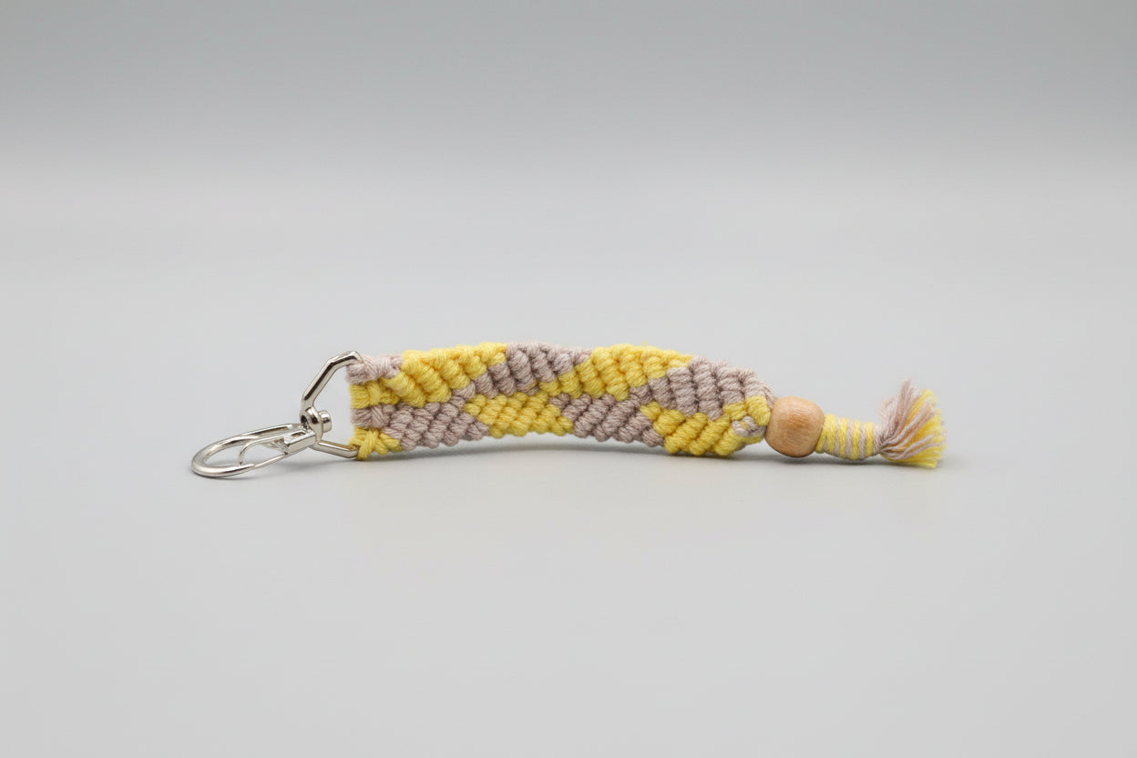 Yellow and gray striped keychain with a bead on a black background